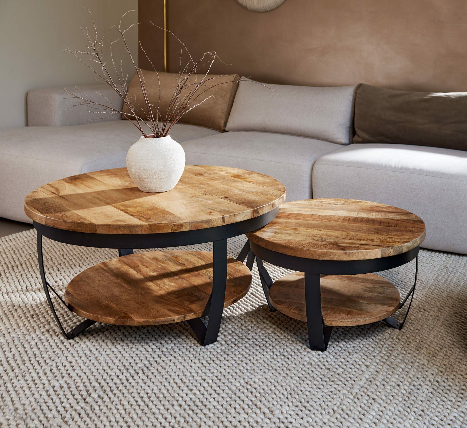 Salontafel 2 delig rond industrieel gemaakt van mango hout en zwart metaal in een moderne woonkamer.