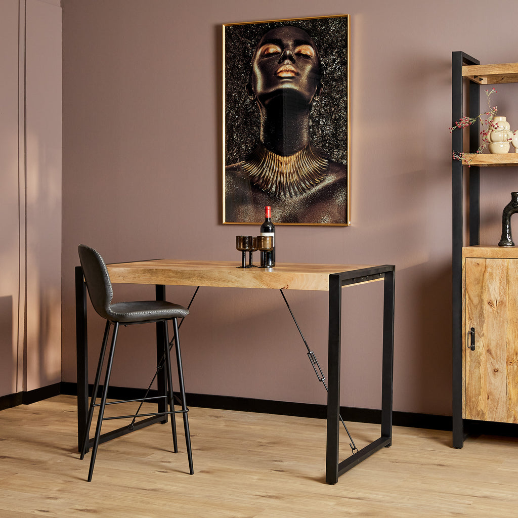 Moderne zwarte barkruk met rugleuning en zwart metalen poten en een bartafel van mango hout en zwart metalen poten in een moderne eethoek met roze muren.