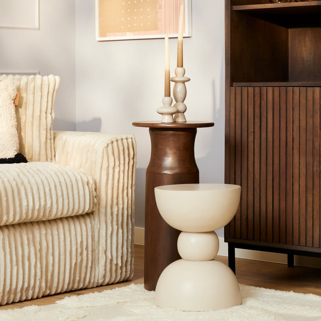 Goedkope bijzettafels in unieke geometrische vormen in glimmend wit en donker koper in een moderne warme woonkamer met een zachte witte bank en een eiken kast.