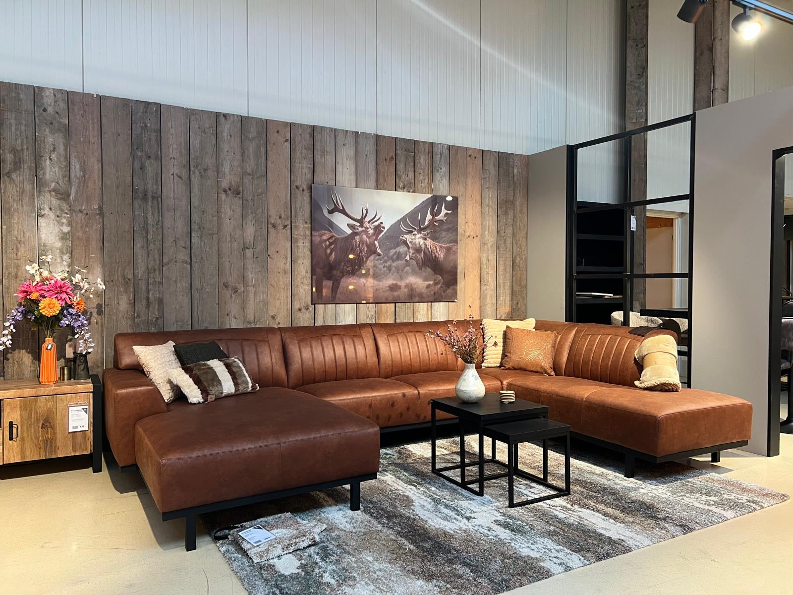 Showroom van De Friese Meubeljongens hoek met een woonkamer setting met een bruin leren bank en moderne meubels.