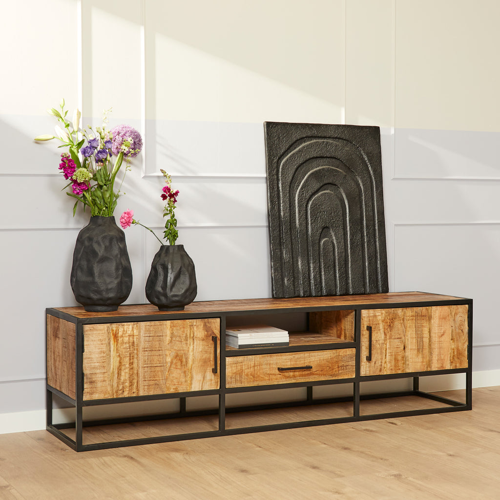 tv-meubel van mango hout en zwart metaal met moderne decoraties er op voor een witte muur.