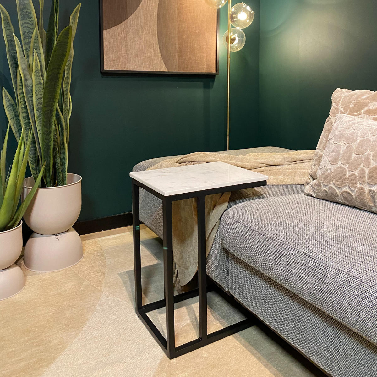Bijzettafel van marmer en zwart metaal in een moderne woonkamer.