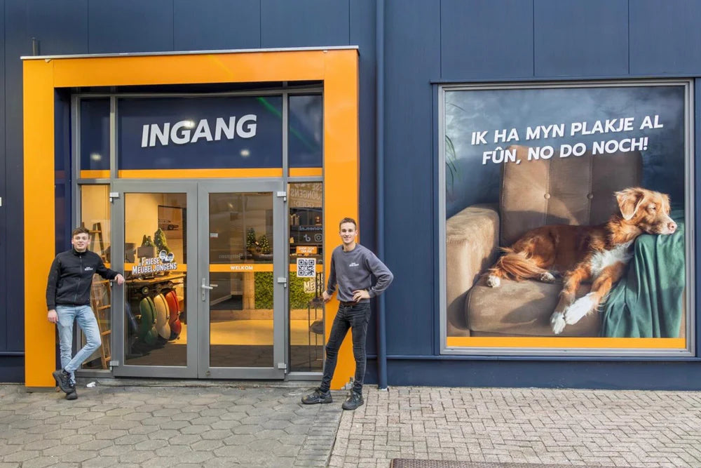 Ingang meubelzaak De Friese Meubeljongens met de eigenaars naast de voordeur.