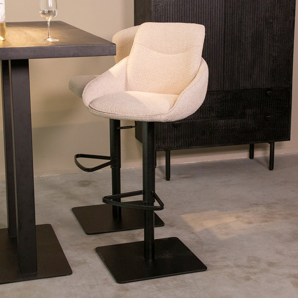 Draaibare barkruk van zachte witte stof en zwart metalen poot in een moderne eetkamer.