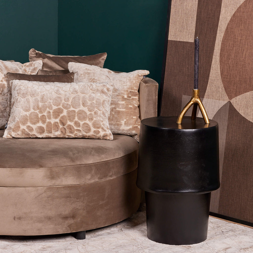 Goedkope zwart metalen bijzettafel in een trendy moderne zithoek met donkere muren naast een roze stoel met zachte sierkussens.