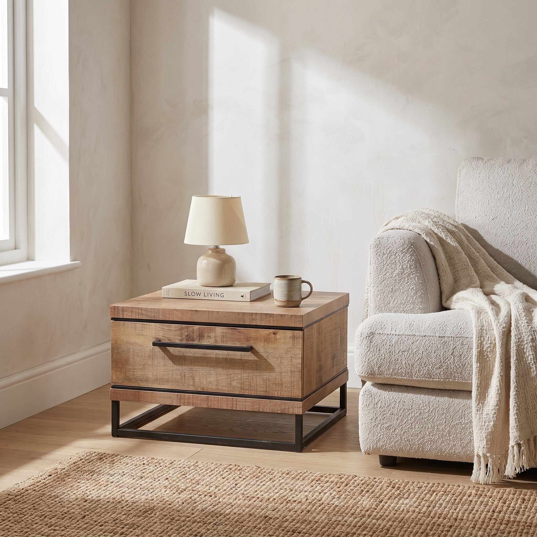Hoektafel Lynn 67 cm in mango-look met mat zwart metaal, sfeerfoto naast een boucle bank