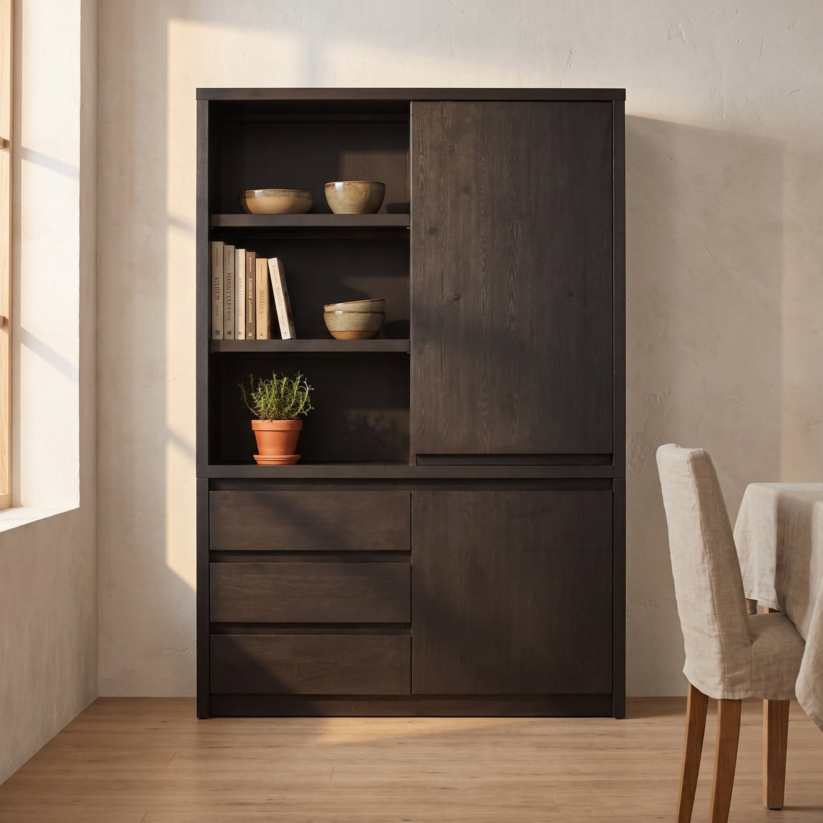 Wandkast Modena 138 cm met 2 deuren, 3 lades en 3 open vakken in donkere Noir-afwerking, sfeerfoto in eetkamer