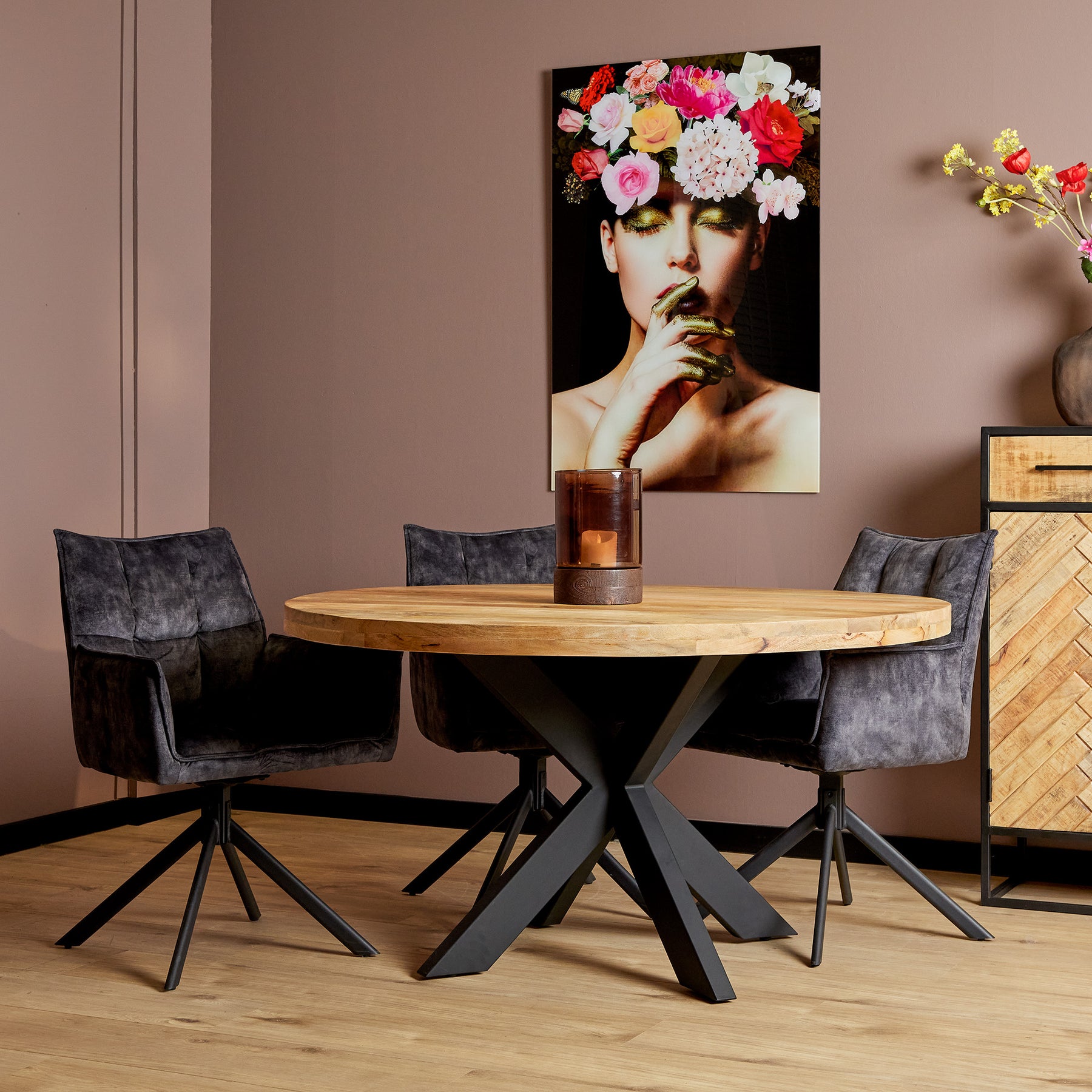 Ronde eettafel 130 cm van mangohout en zwart metaal met 3 eetkamerstoelen er omheen in een trendy moderne eethoek.