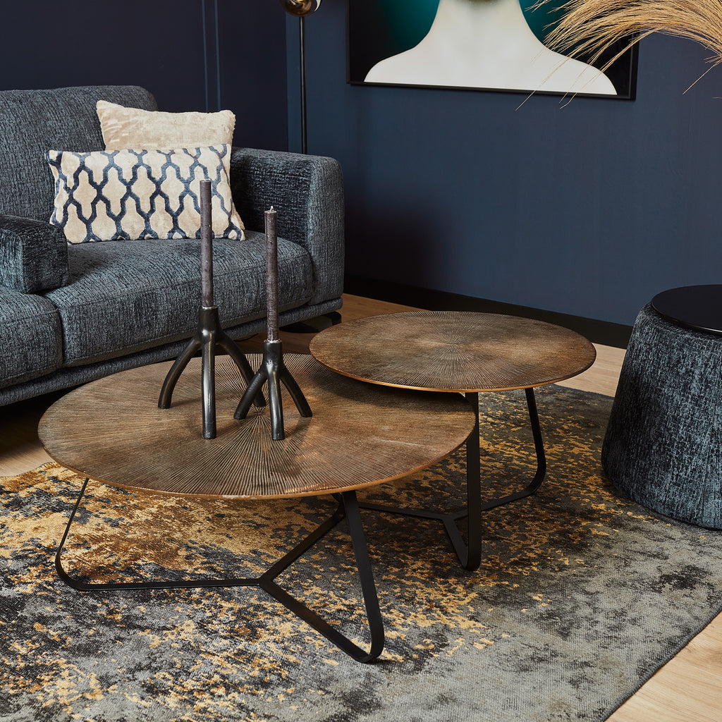 Salon tafel 2 delig rond van kopen stijl blad en zwart metalen poten in een moderne woonkamer met donker blauwe muren en goud accenten.