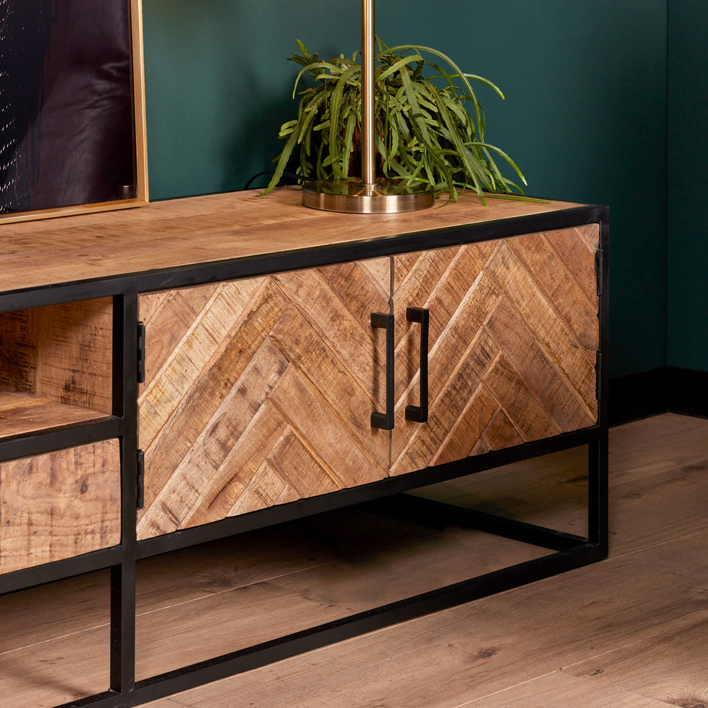 Close up van een mangohout tv meubel in een modern interieur met blauwe muren.